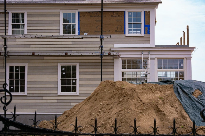 House under renovation with scaffolding and dirt pile.